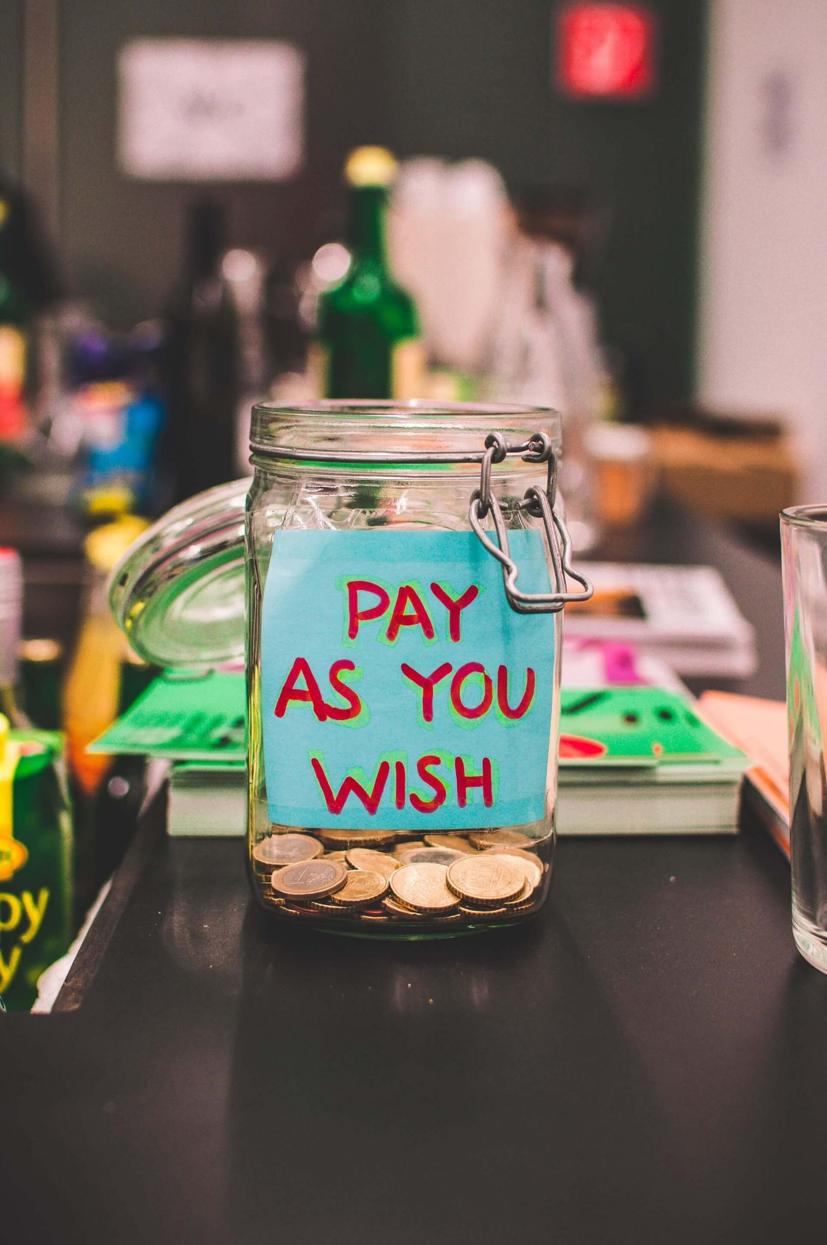 A money jar with a sign saying “pay as you wish” A money jar with a sign saying “pay as you wish” - Monetize Your YouTube Channel